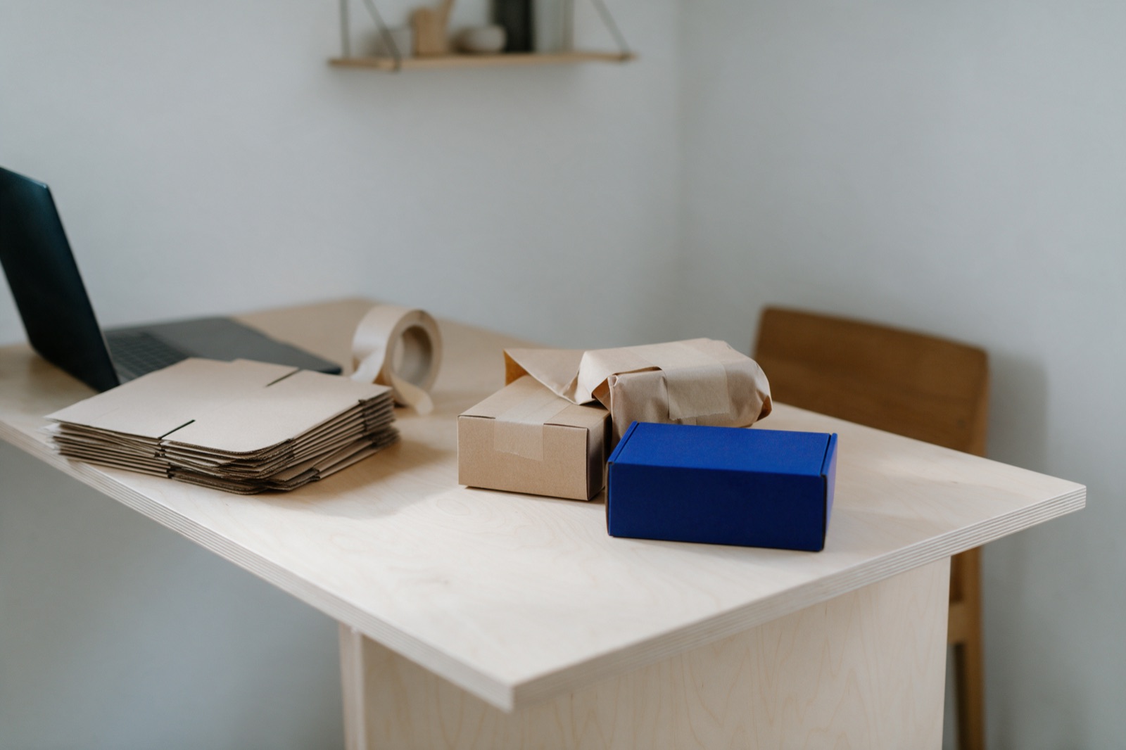 A small ecommerce packing bench with a modest stack of flat kraft mailer boxes, paper tape and made-up parcels