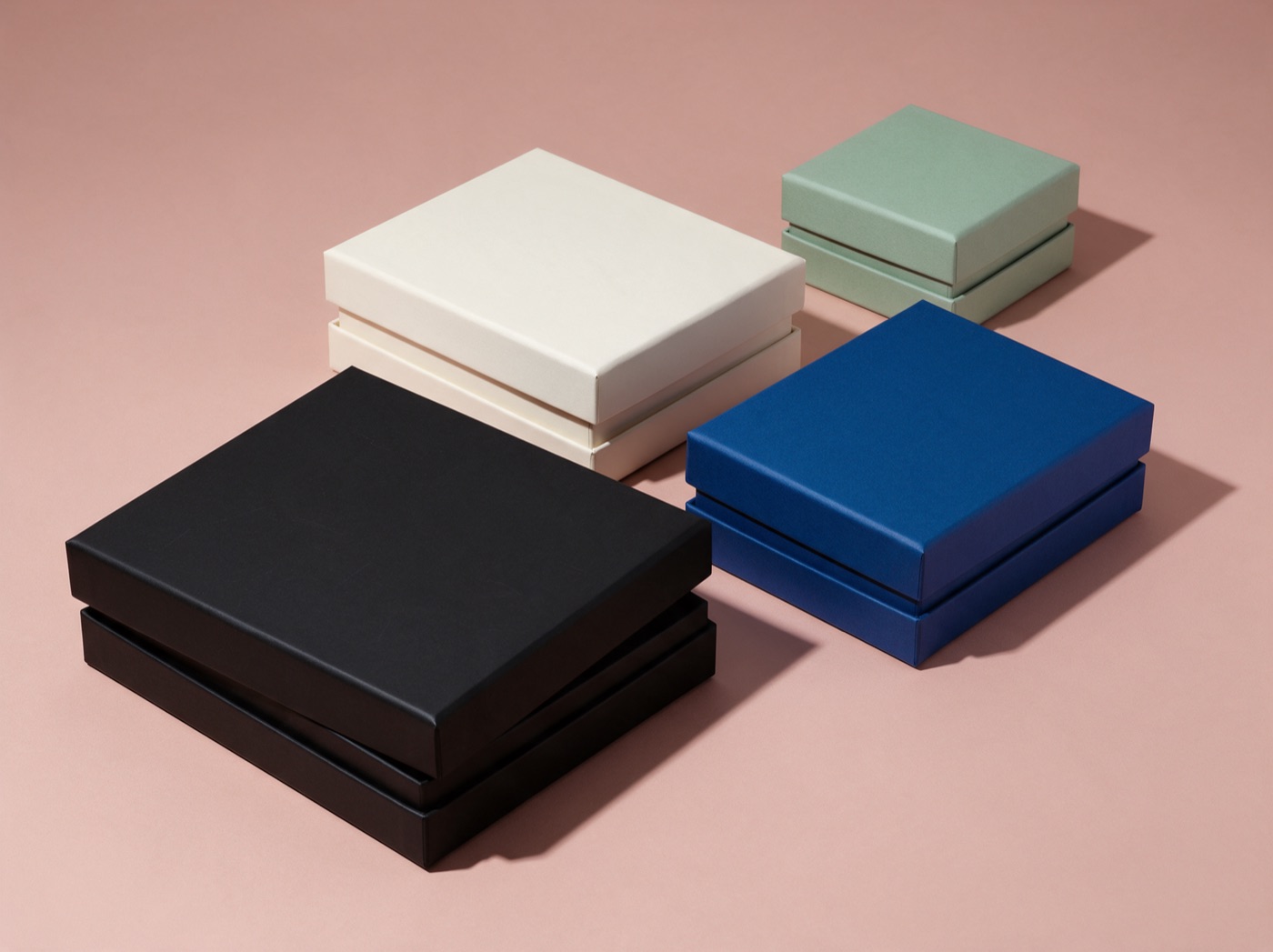 Rigid lid-and-base boxes with lids offset, in black, bone, cobalt and sage